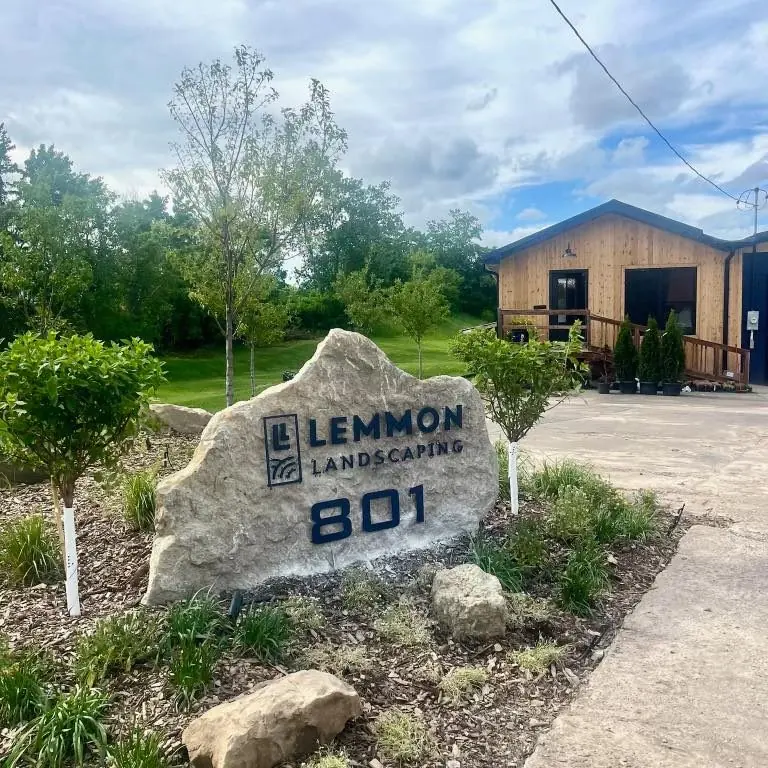 The Lemmon Landscaping sign lettered on a limestone boulder at 801 North Green Street, with a wood-clad building and a new planting bed behind it