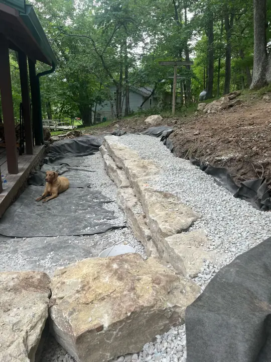 A gravel path edged with large flat boulders beside a house, a dog lying on the path
