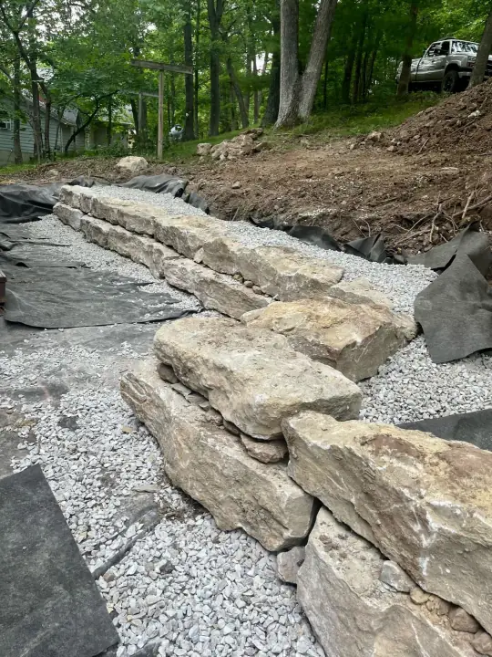 Large boulder steps set on a slope with gravel and black landscape fabric