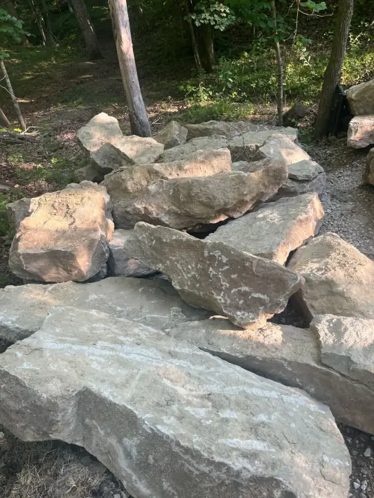 Large stacked boulders on a gravel slope in the woods