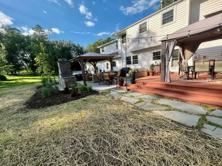 A flagstone path across straw-covered new lawn toward a deck and pavilion